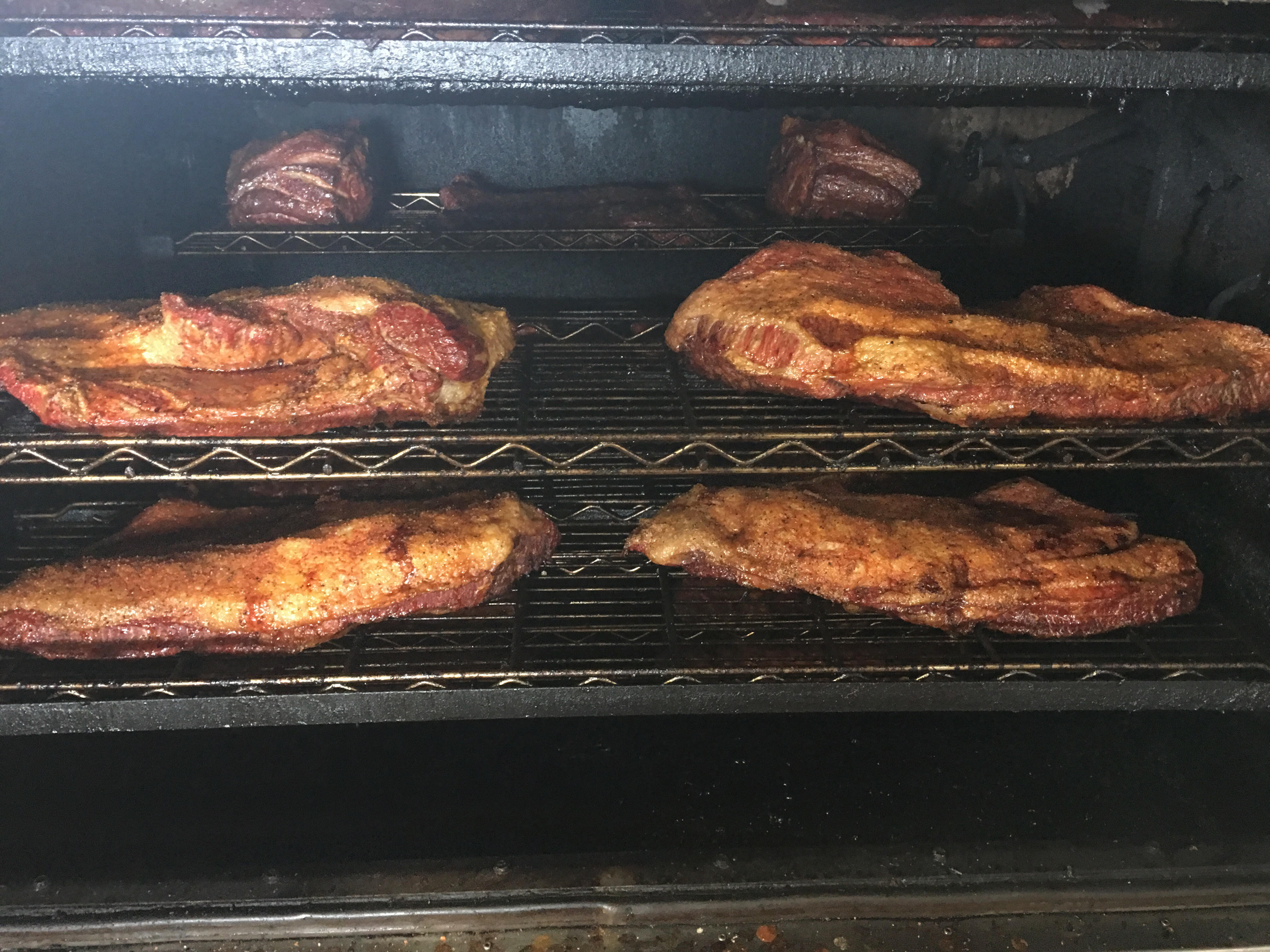 Mesquite-smoked brisket and beef ribs smoking low and slow inside R & R BBQ's smoker in Stephenville, TX