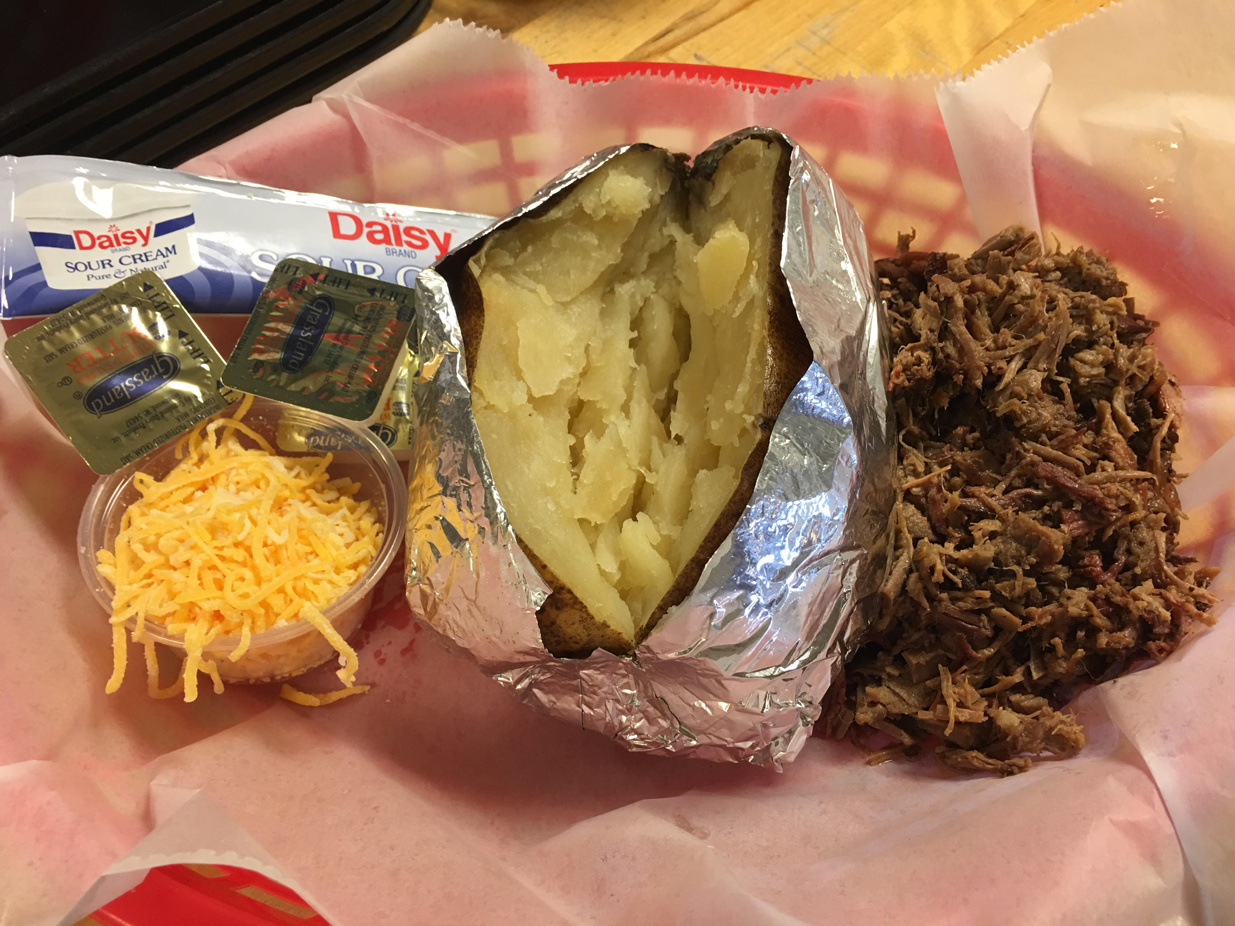 Loaded baked potato topped with pulled beef, cheese, and sour cream at R & R BBQ